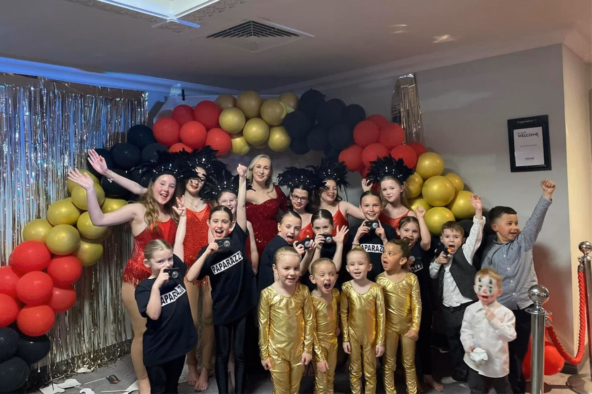 Group of children in Oscar themed outfits in front of party balloon arch