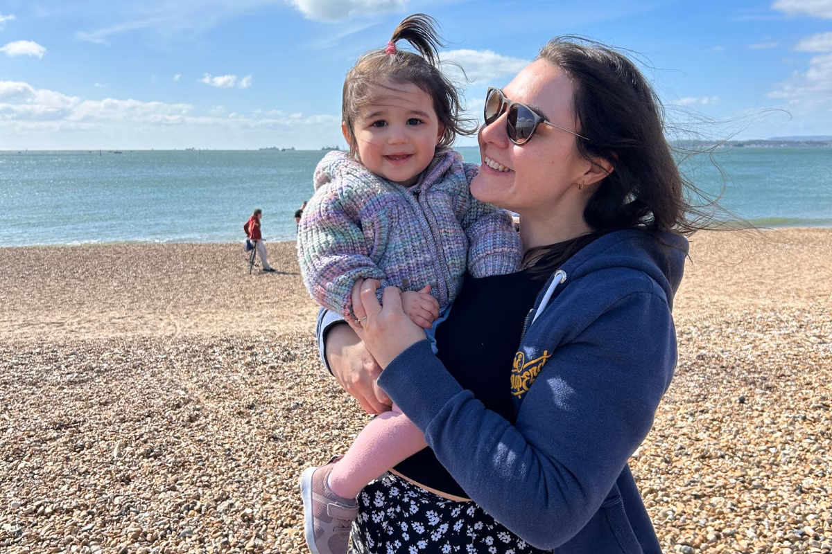 Mum holding daughter on a beach