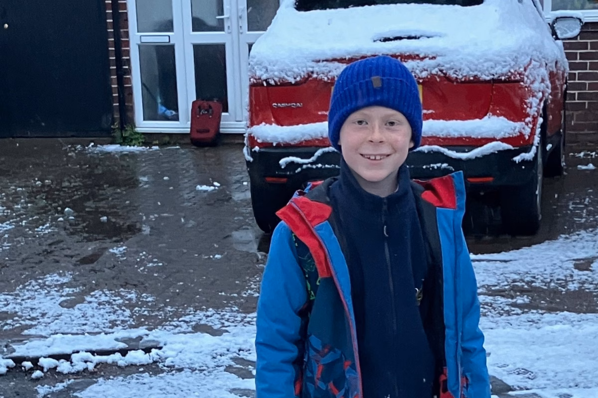 Boy standing outside house in the snow