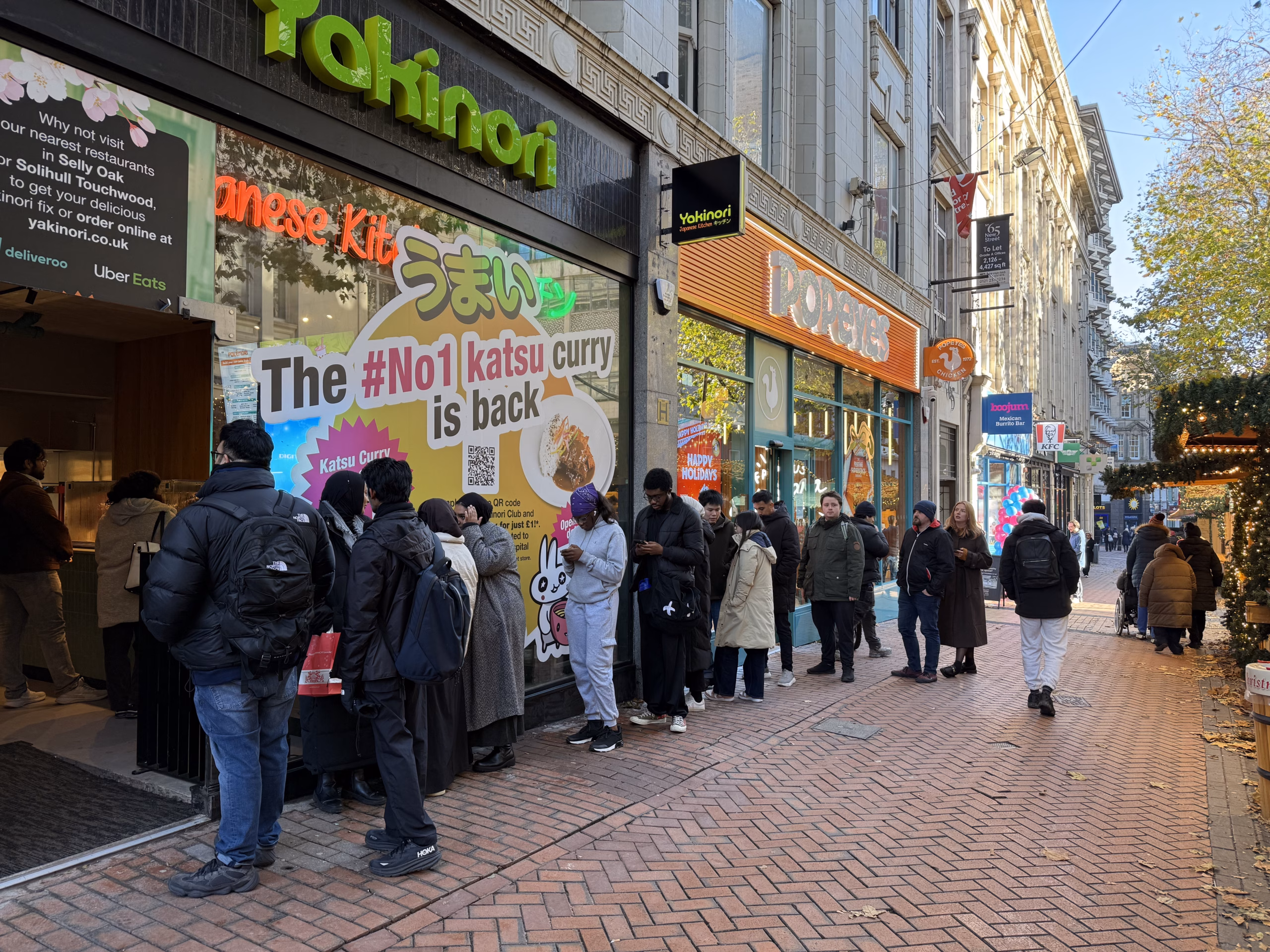 A line of people queuing up outside a Yakinori restaurant.