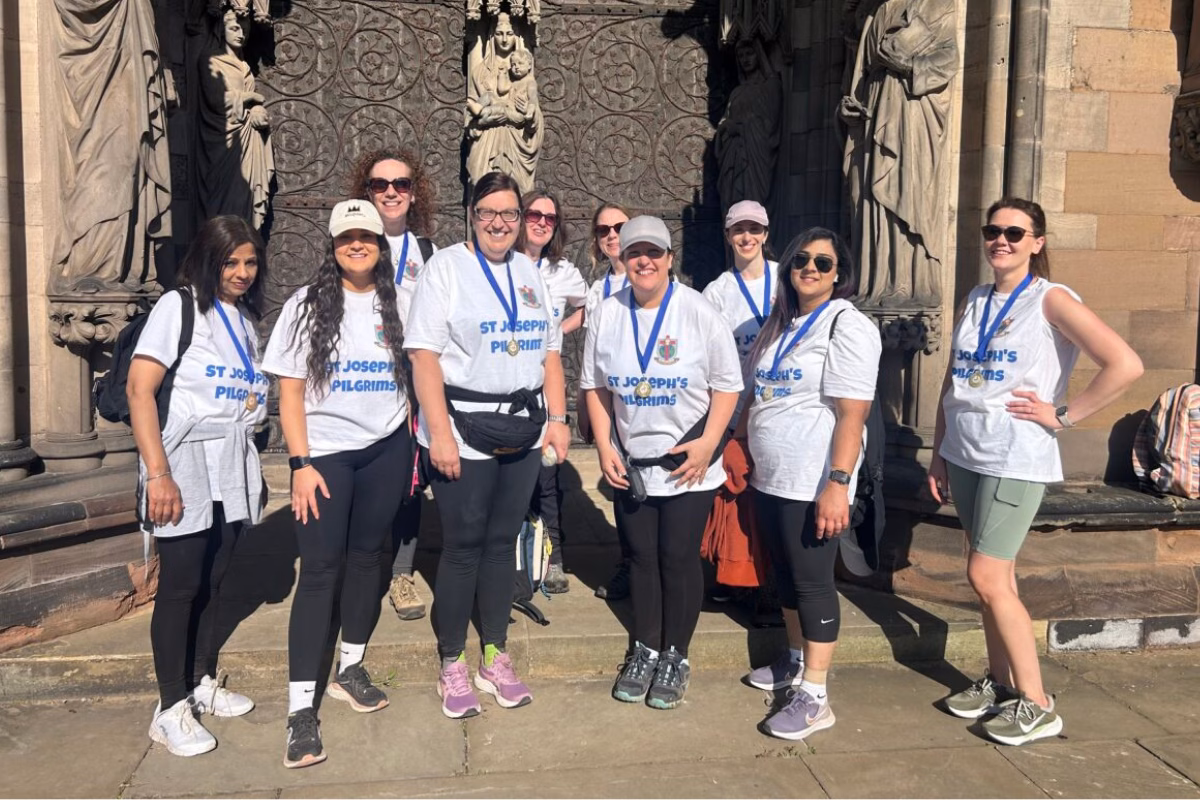 Group of St Joseph's pilgrims in white t shirts wearing their fundraising medals and smiling
