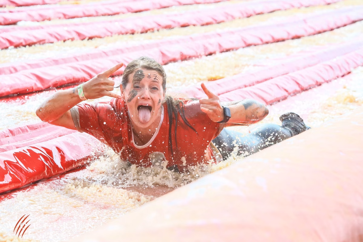 Mum smiling while tackling inflatable obstacle course in muddy Wolf Run for charity