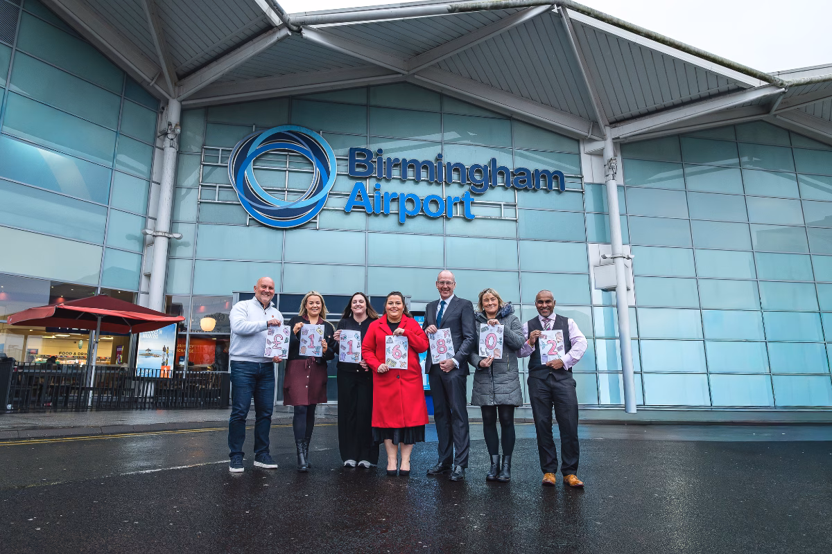 BHX team outside airport holding fundraising total figure of £116802
