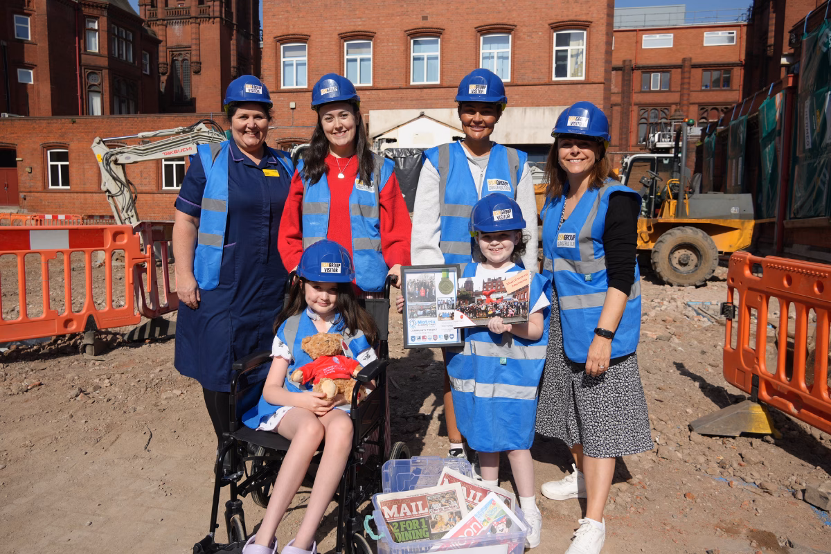 Natalie Harford, Miranda Williams and patients Ava and Foxx with their parents standing outside the construction site with items from the capsule