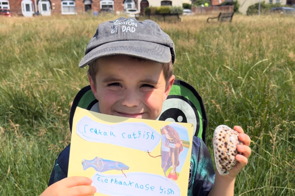 Young boy holding up fish collage outdoors