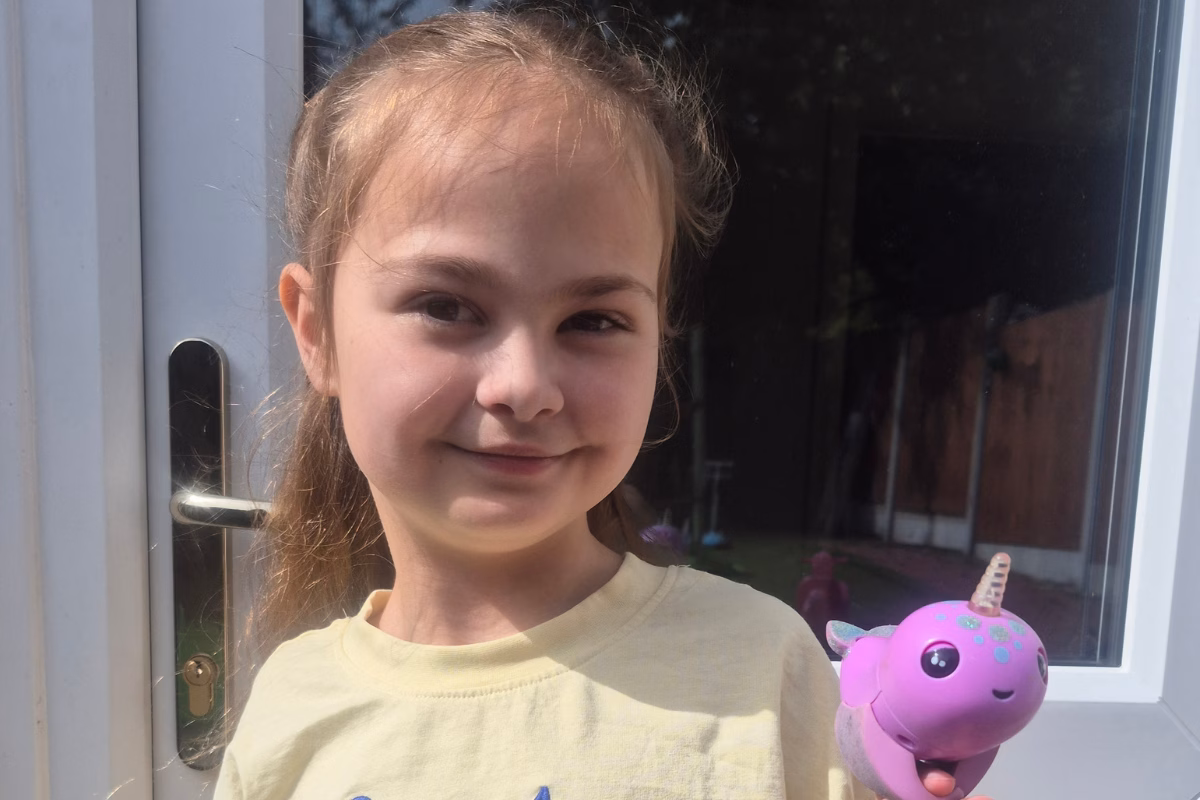 Girl holding up purple plastic Narwal toy