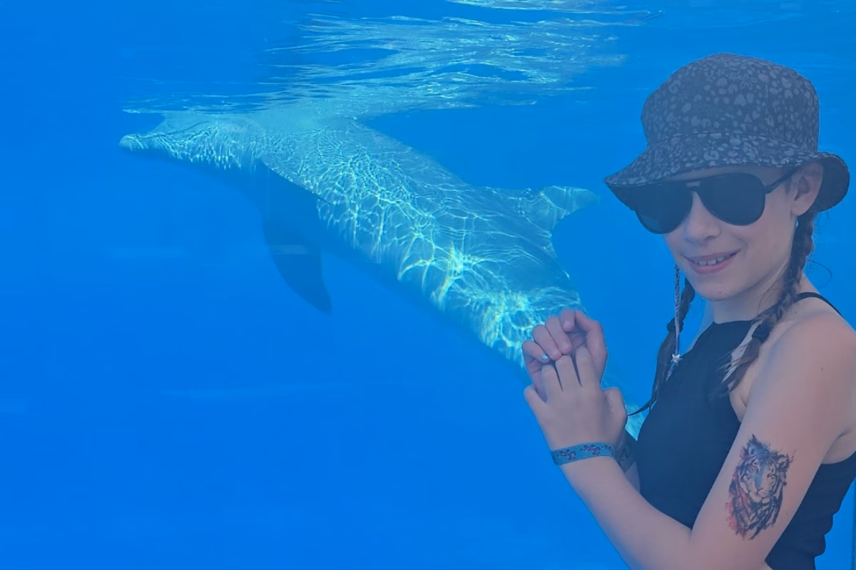 Teenage girl on holiday pointing at dolphin in large tank