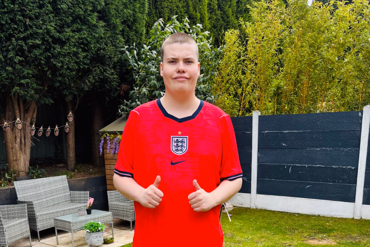 Teenage boy in red England shirt standing in garden and doing two thumbs up