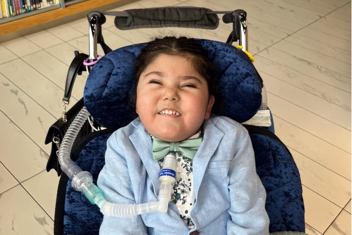 Young boy in adapted wheelchair with tracheotomy