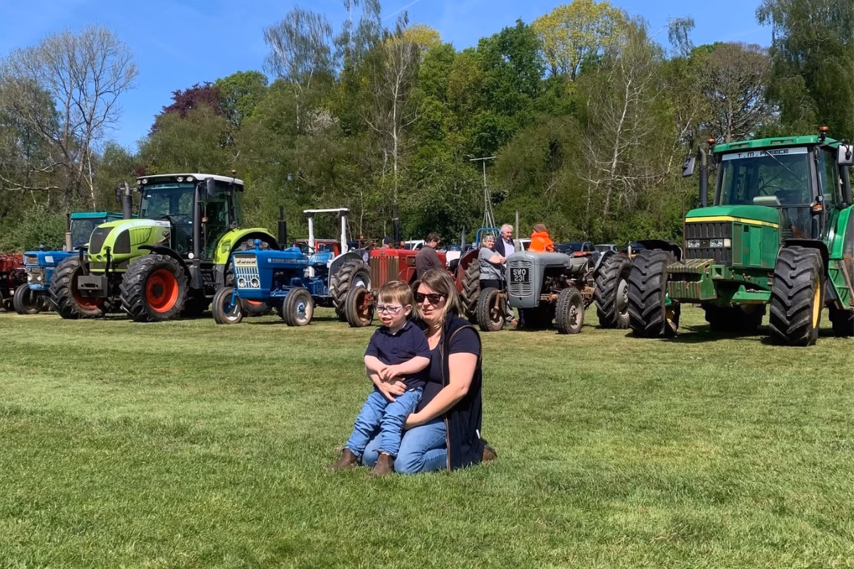 Woman hugging boy in field with tractors in background