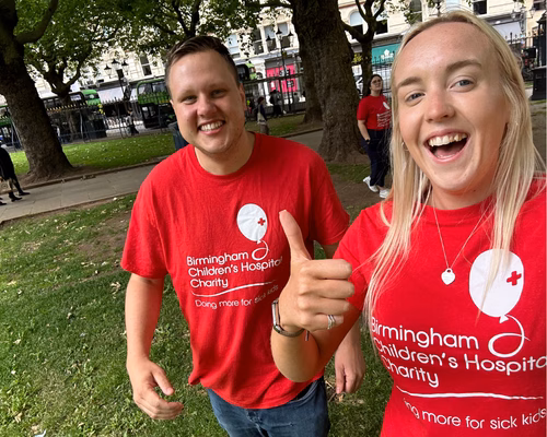 A man and a woman pictured from the waist up, wearing red t-shirts
