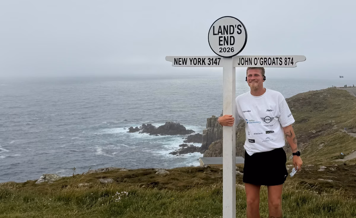 Laurence standing next to Lands End sign on UK coastline