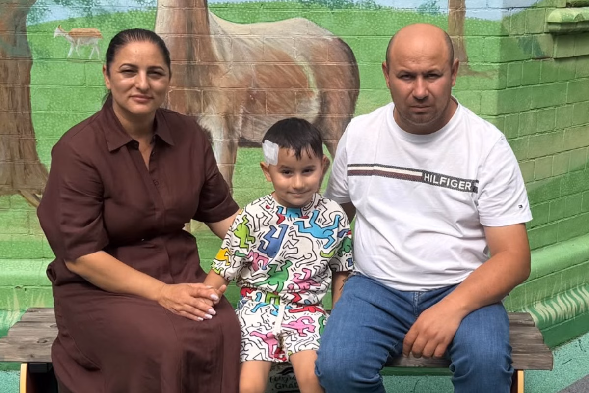 Child with plaster on head (centre) next to mum and dad, seated
