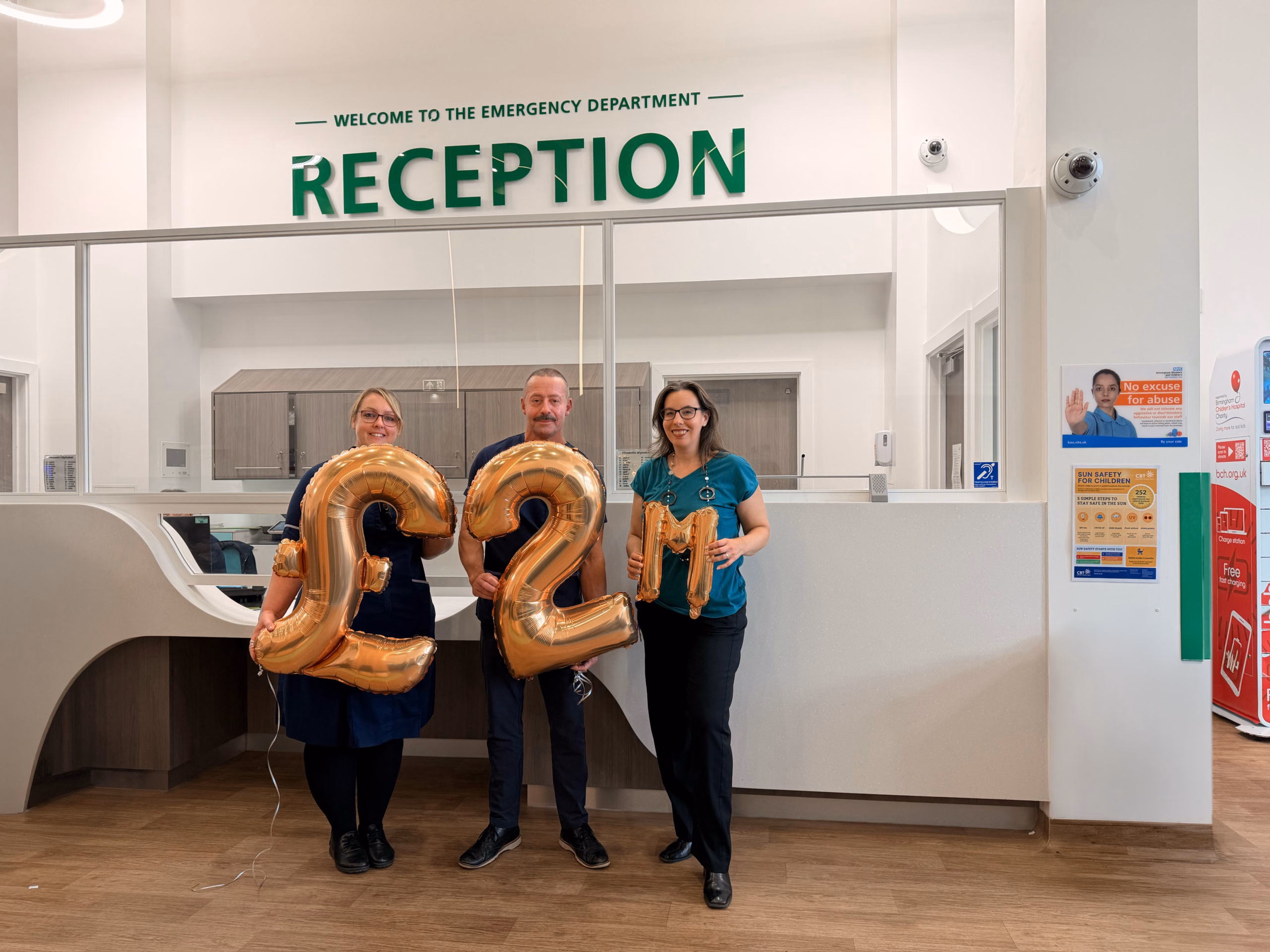 Three staff holding £2m balloons in Emergency Department reception