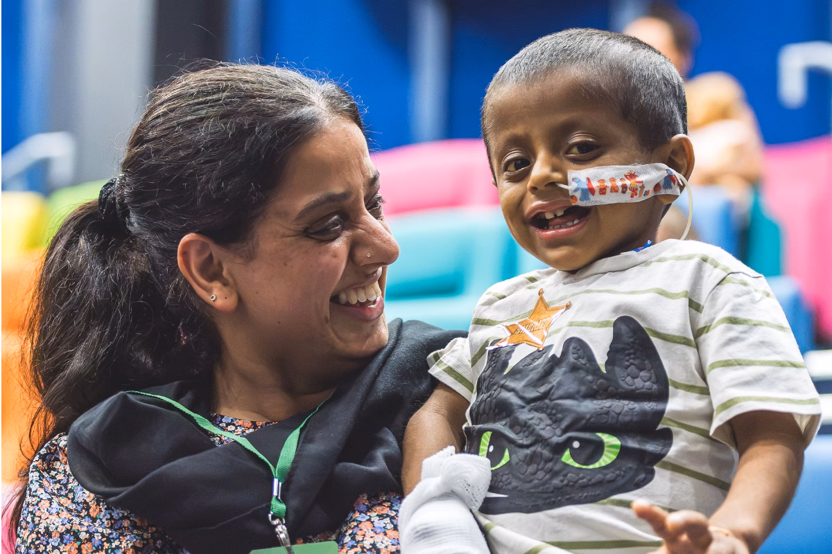 Smiling mum holding up toddler with nasal tube