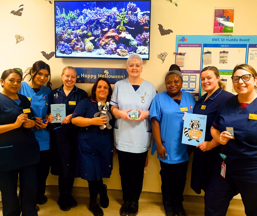 Staff holding raccoon toy and booklets in Tracheostomy ward