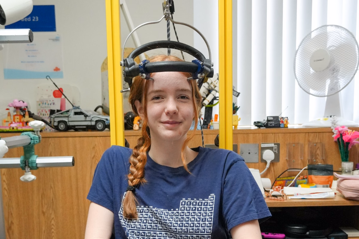 Chloe with halo machine attached to head and walker in hospital