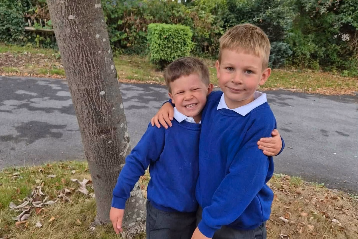 Boy grinning next to older boy in school uniforms