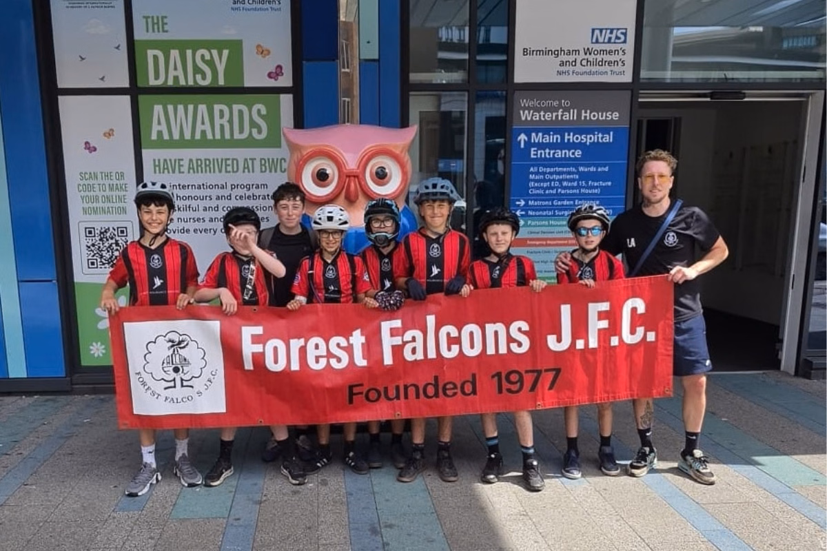 Group of kids outside Children's Hospital holding red banner with Forest Falcons J.F.C.