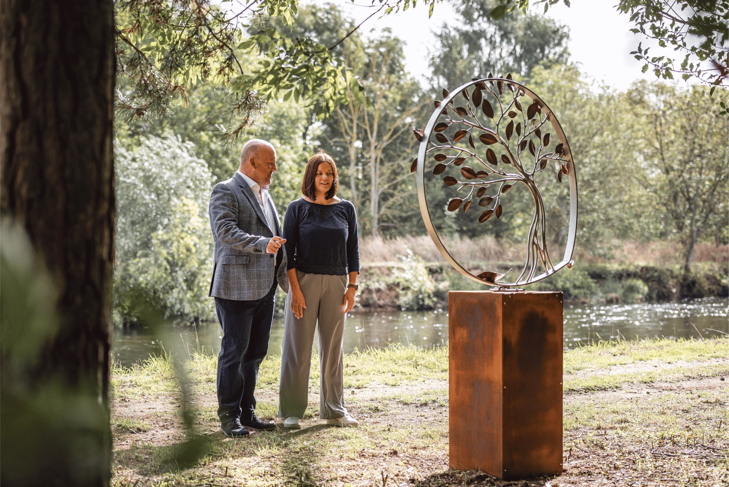 Mark Brider CEO and Emma Hill bereaved mum looking at tree sculpture in memorial gardens