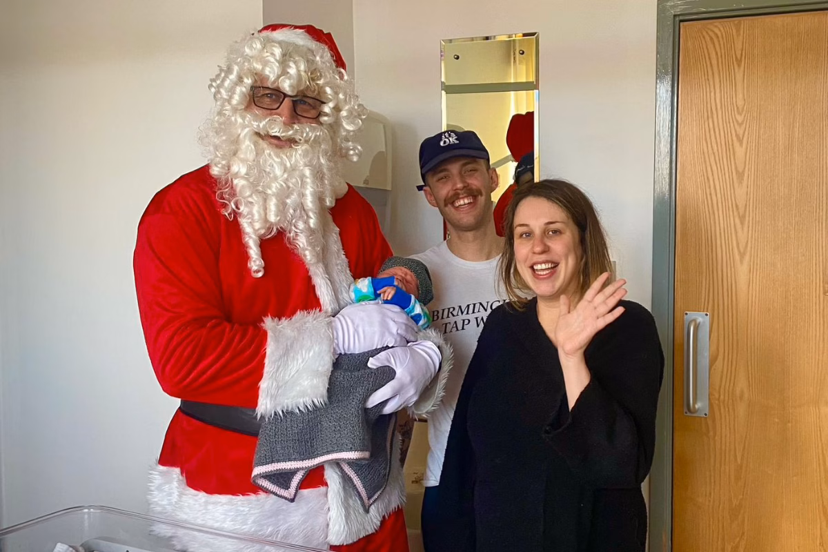Baby Dougie being held by Santa, with parents waving