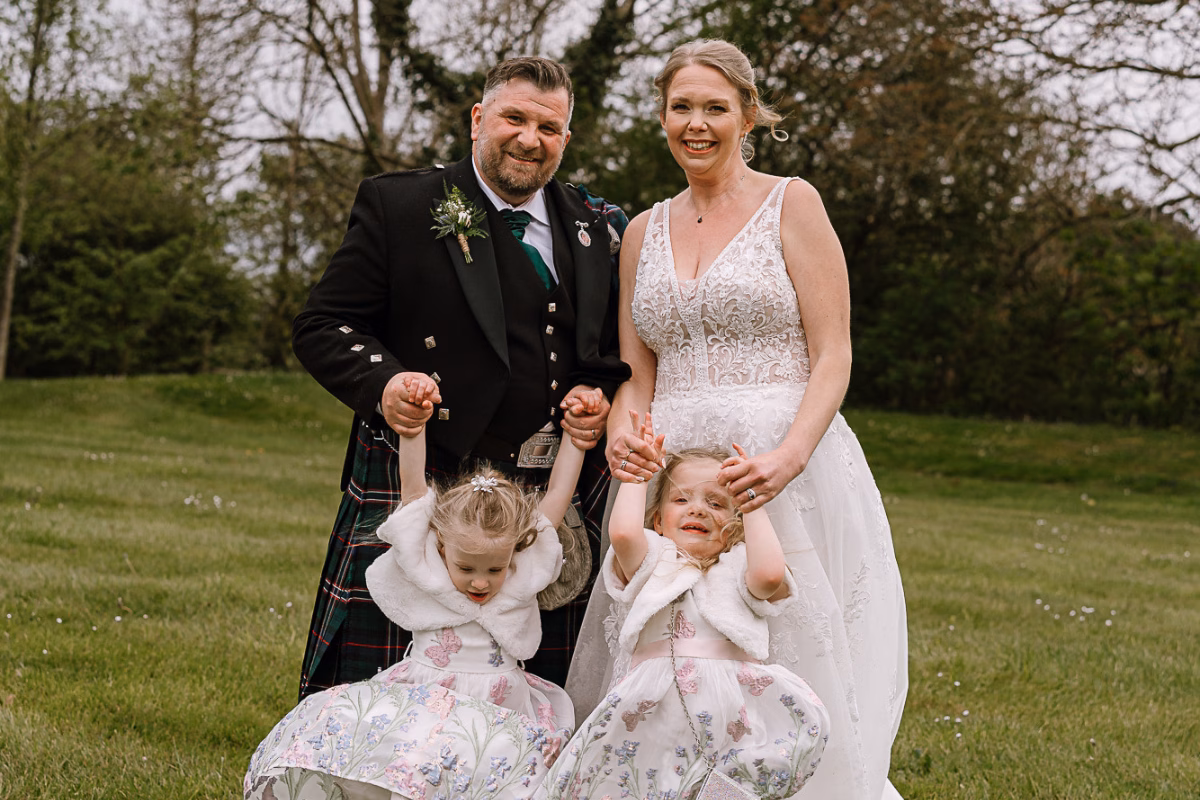 Sophie and Kevin Farnell on their wedding day holding hands with their two daughters