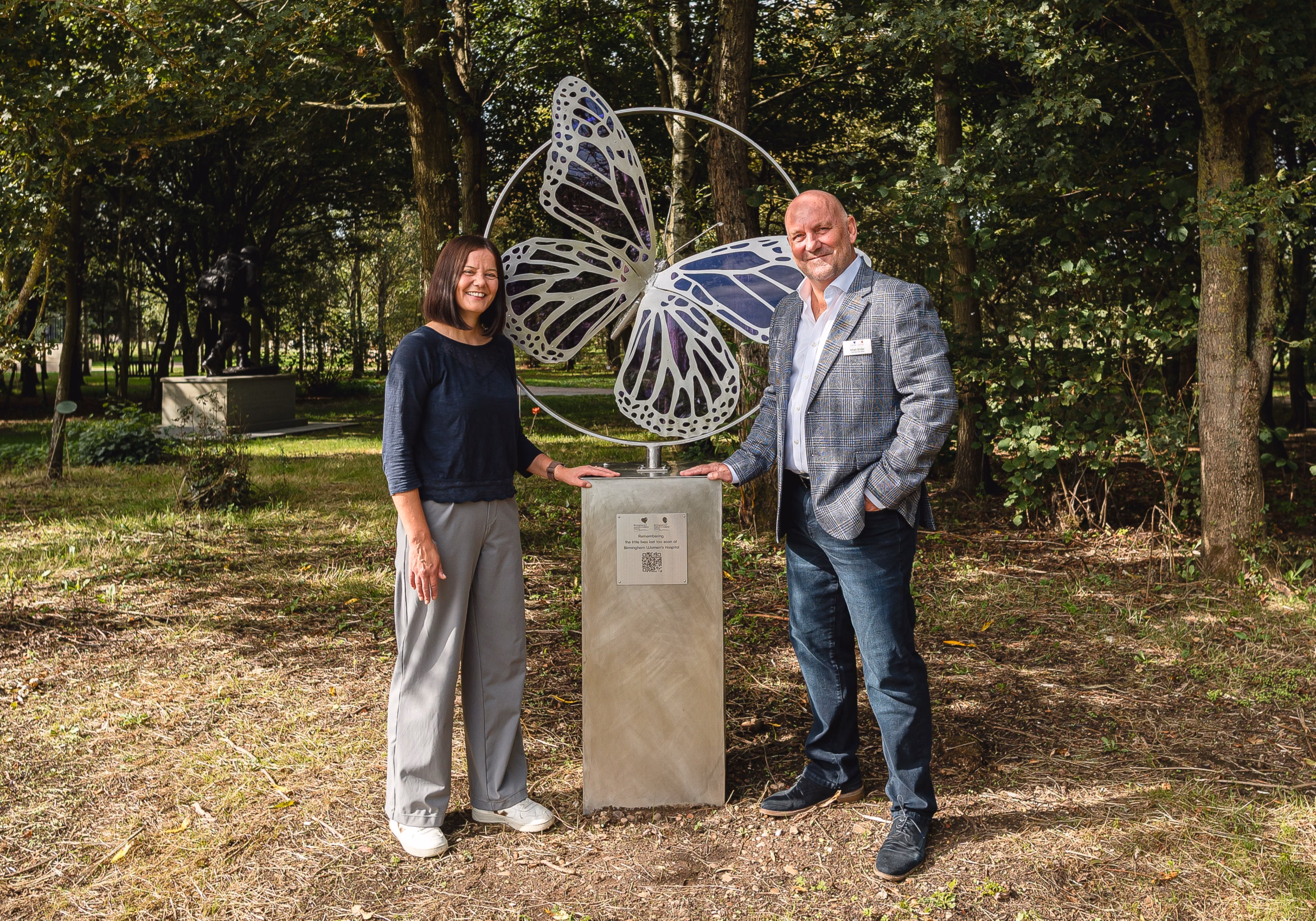 Emma and Mark standing next to butterfly sculpture in memorial gardens